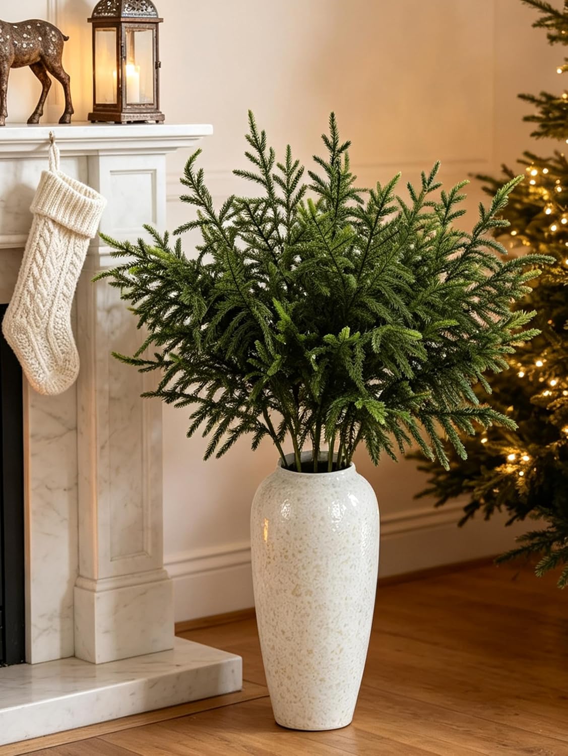 Tall Norfolk pine stems in a vase next to a fireplace and stocking