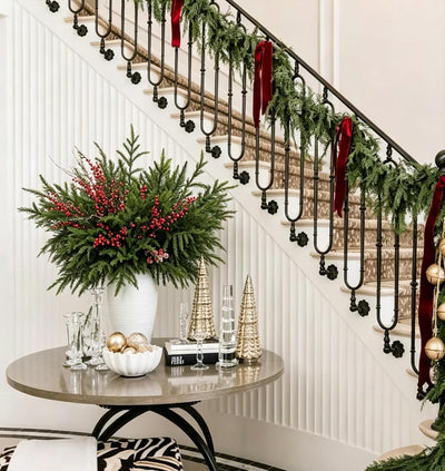 Norfolk pine stems with red berries in a vase by a staircase